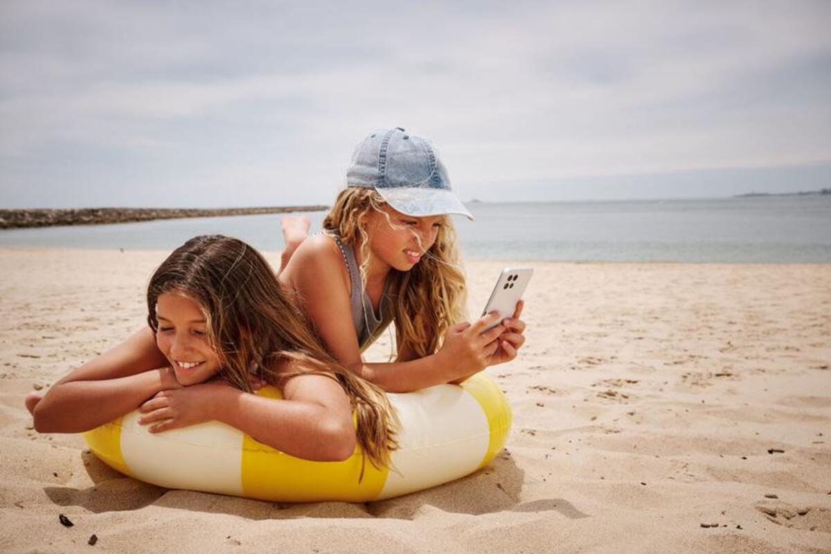 Dziewczynki przeglądają telefon podczas pobytu na plaży