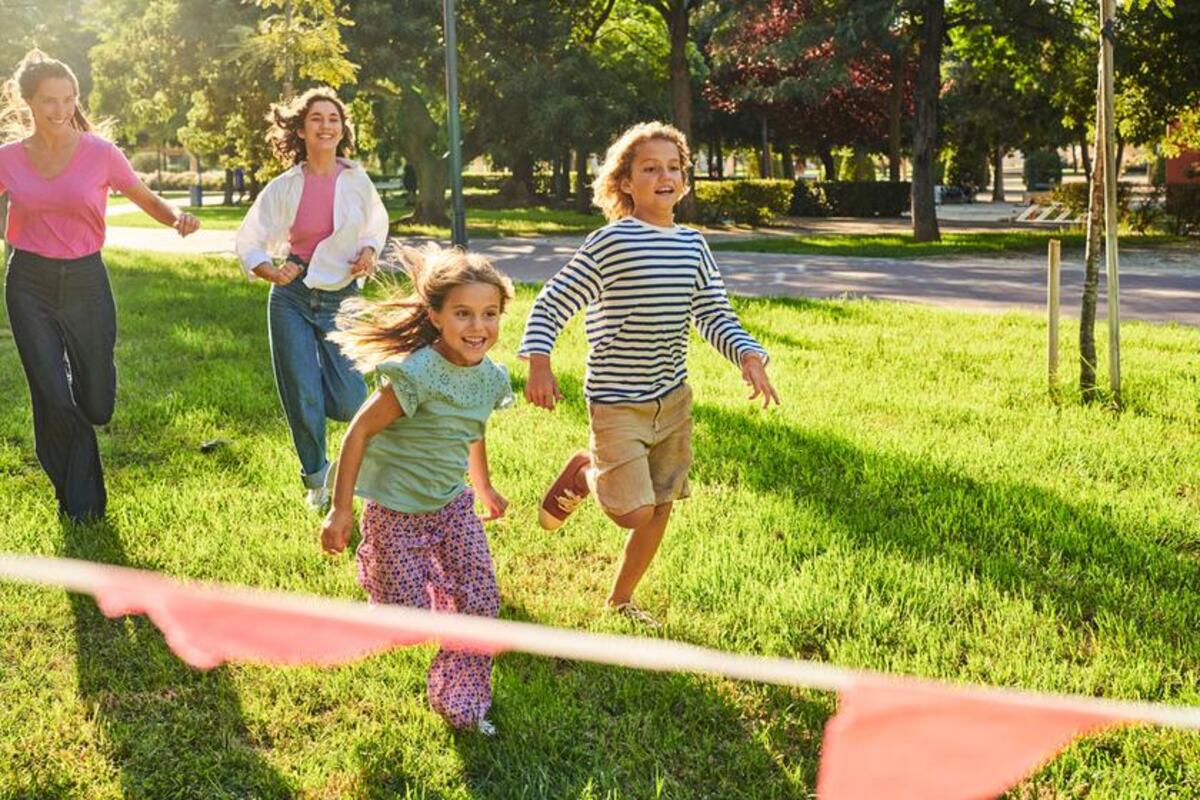 Uśmiechnięte dzieci biegną po trawie w parku.